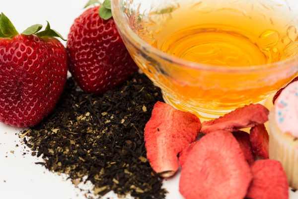 closeup of strawberry cupcake black tea with the flavors' namesakes positioned around the cup of tea