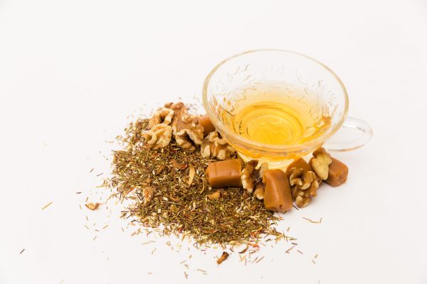 cup of caramel walnut rooibos tea with chunks of caramel and walnuts around it